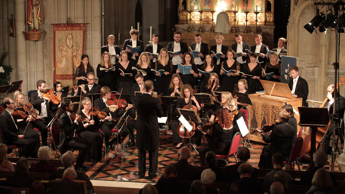 Images of orchestra and choir performing in church with audience